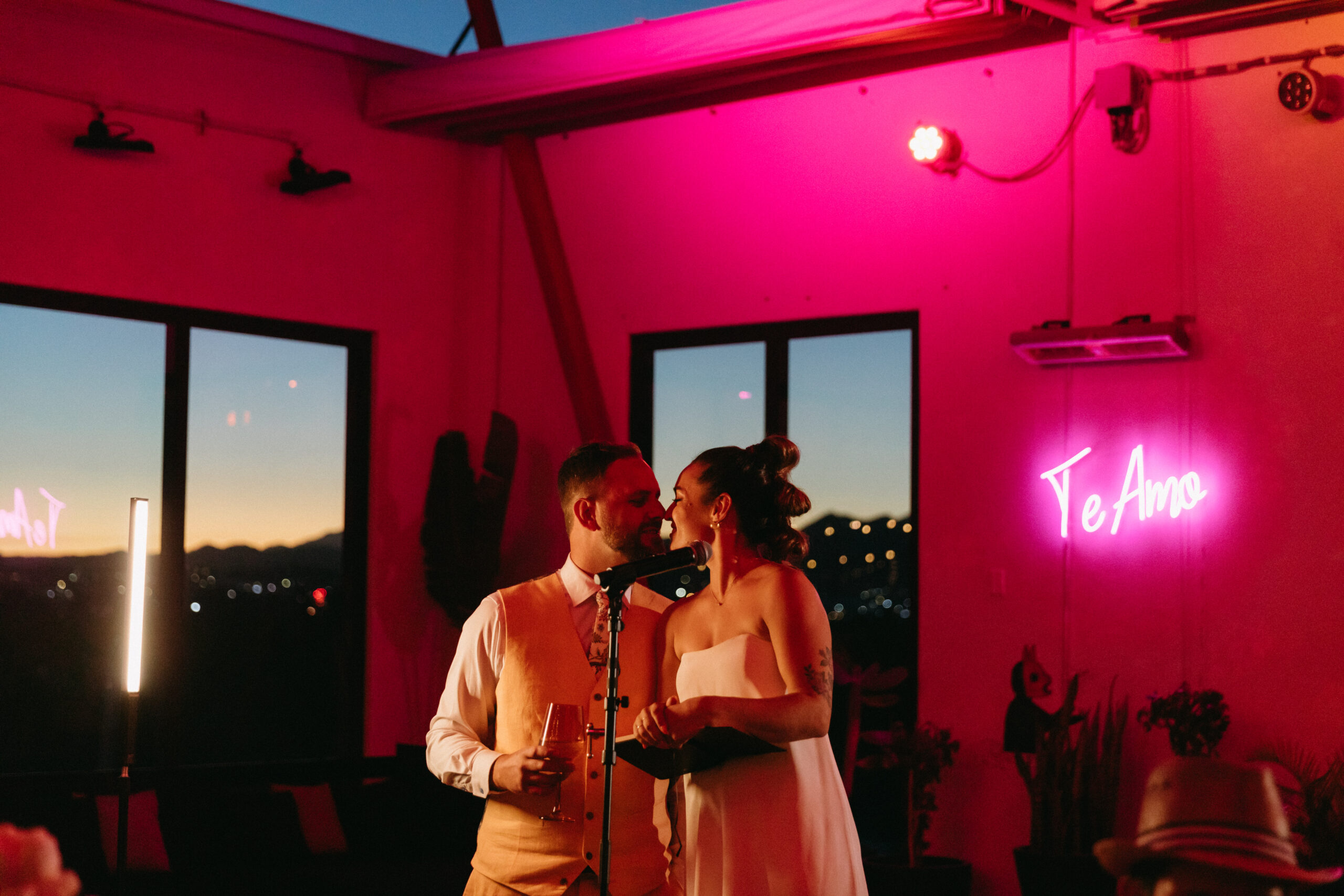 fuchsia pink moody lighting blown glass hearts and disco ball ceiling installation. hotel el ganzo open air dance party wedding te amo neon sign bride and groom welcome speech