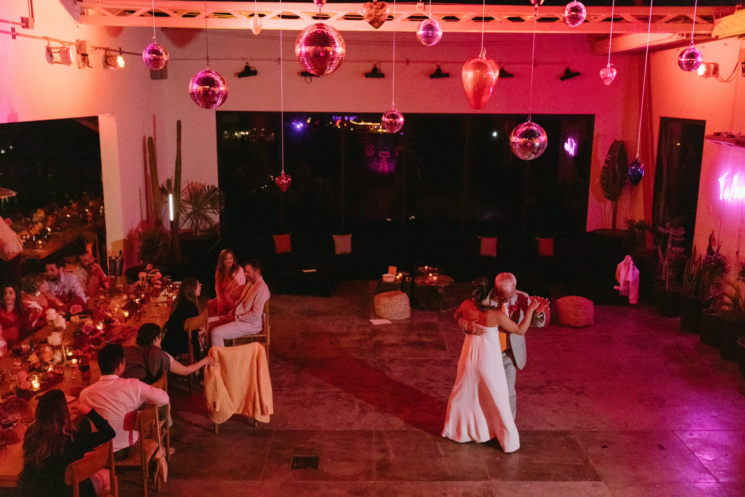 fuchsia pink moody lighting blown glass hearts and disco ball ceiling installation. hotel el ganzo open air dance party wedding te amo neon sign. 
father daughter wedding dance