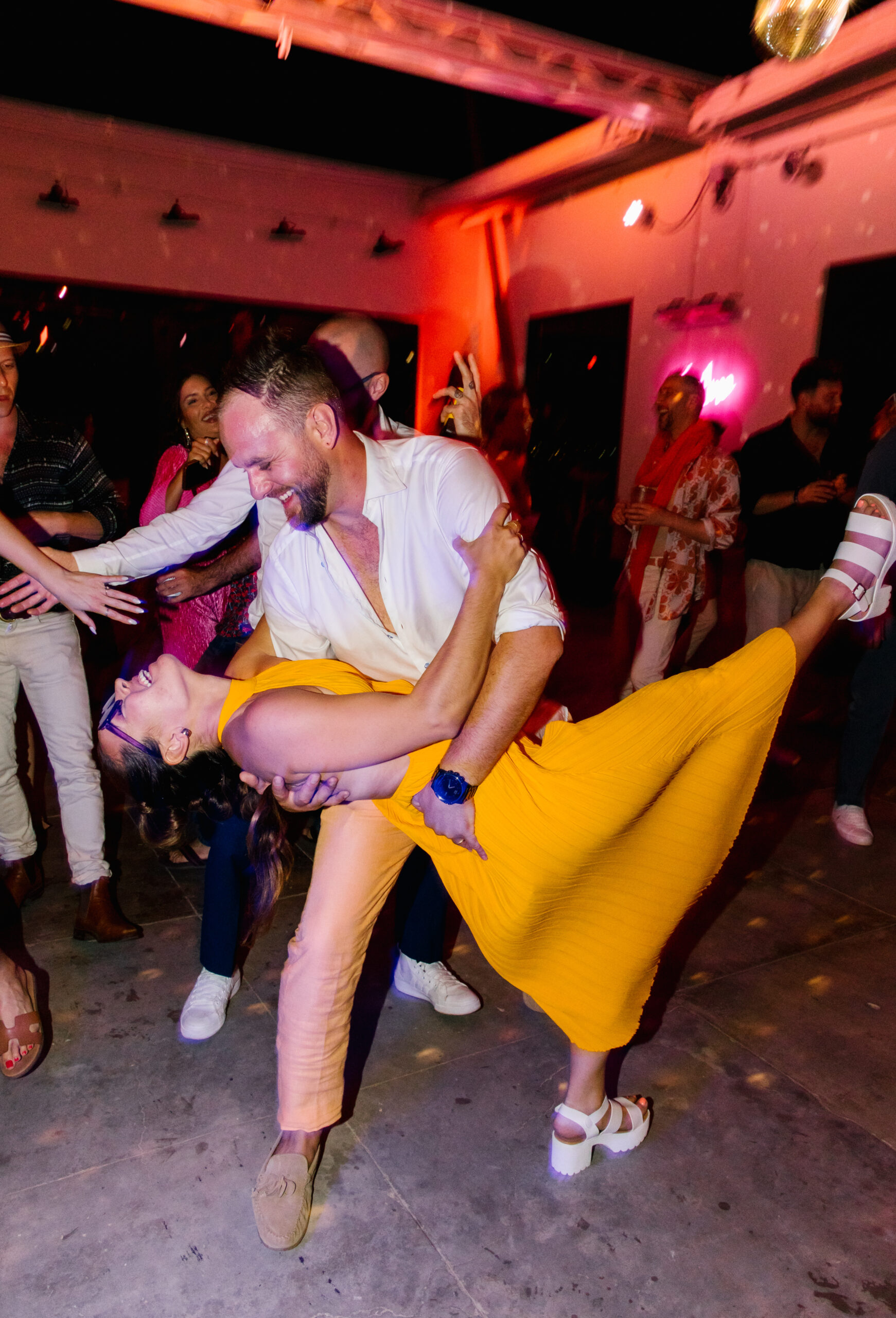 destination wedding mexico open air fuchsia lighting te amo neon sign bride and groom dip dance photo laughing candid wedding photo yellow after party dress