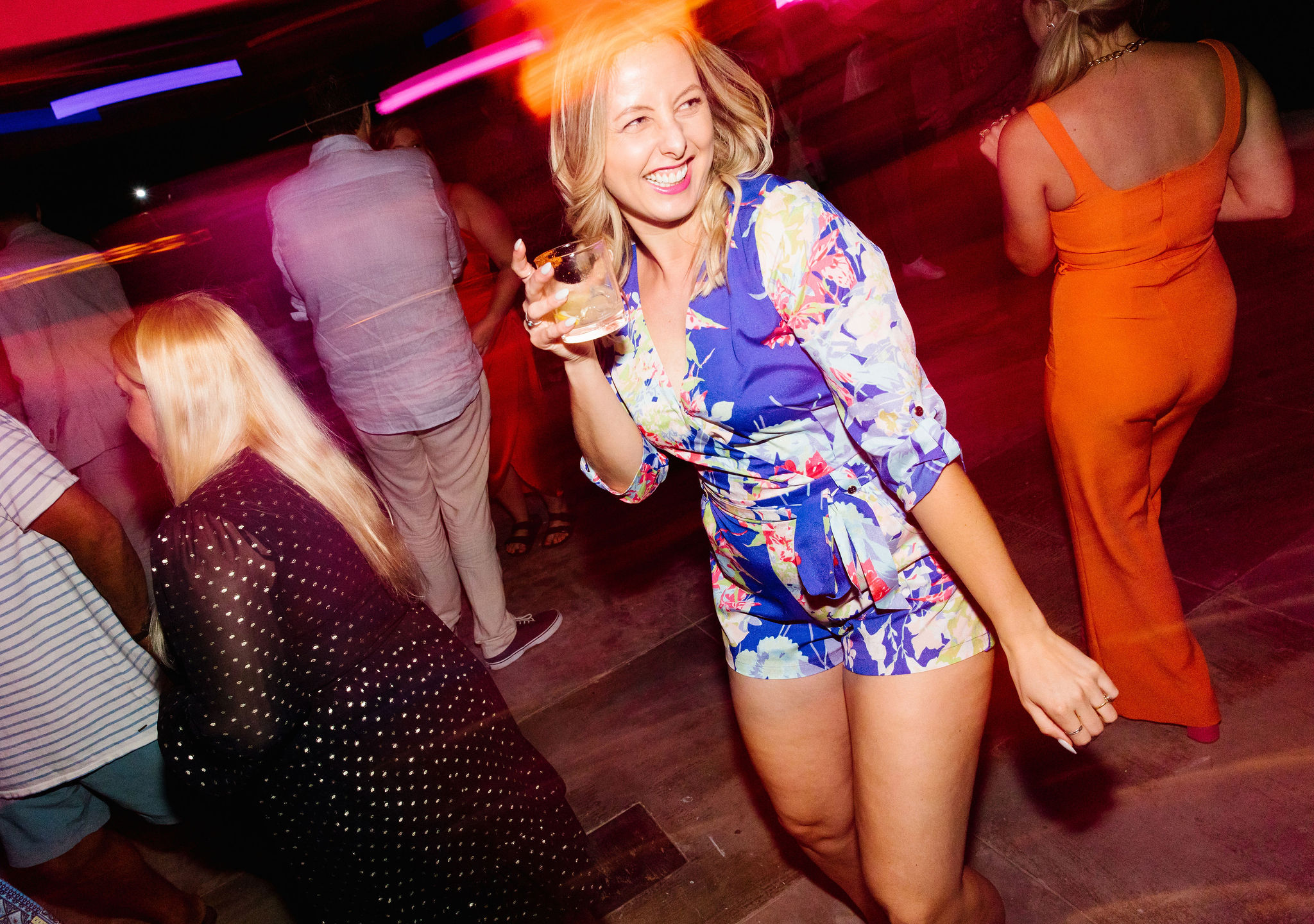 blurry style dance floor photo girl holding drinking big smile candid dance photo colorful wedding guest outfit