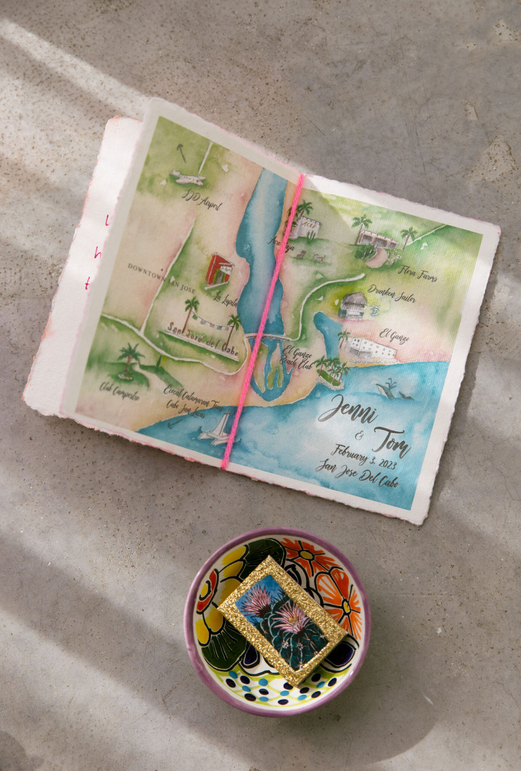 Custom hand painted map of San Jose Del Cabo wedding site. handcrafted ceramic Mexican dish with painted flowers and custom matchbook. Gold glittery matchbook with cactus art printed on box. Watercolor style art by Marketa F. Horton. 