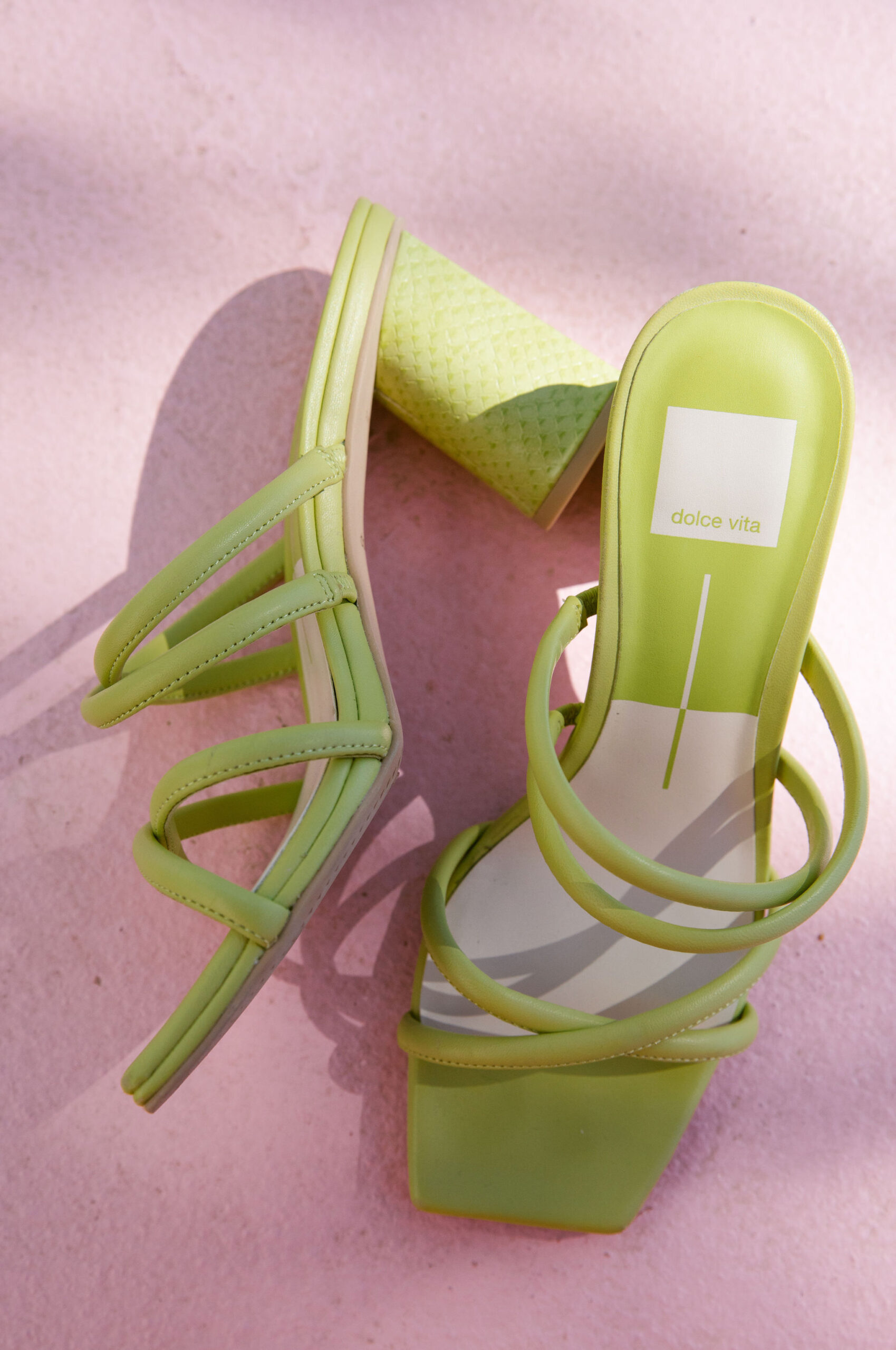 Dolce Vita chartreuse strappy block sandal heels against pink stone background. bridal shoes inspiration. colorful wedding shoes. 