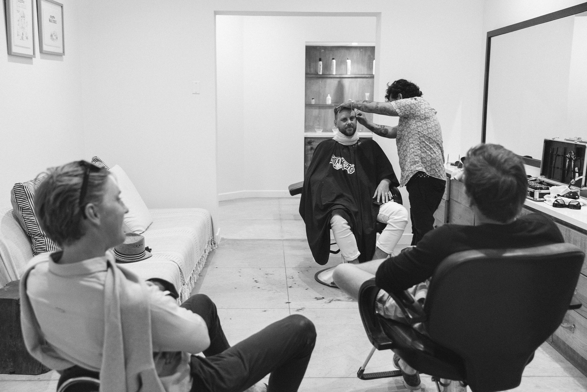 black and white photo of 3 men getting haircut in barber shop at Hotel El ganzo. Groom grooming. groom haircut. groom getting ready