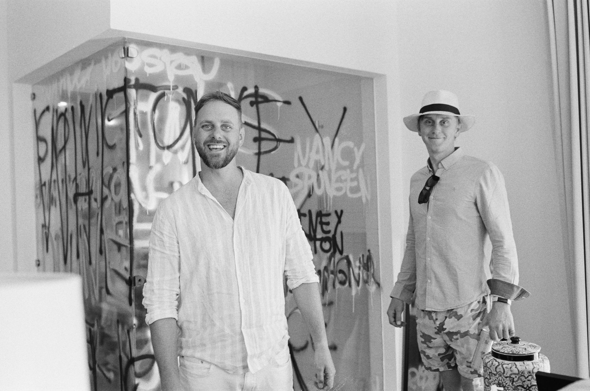 black and white photo groom and groomsman getting ready smiling at the camera. Graffiti art shower Hotel El Ganzo suite. destination wedding.