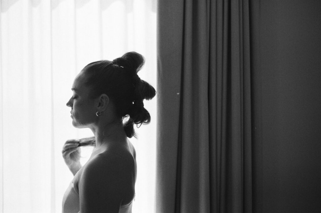 black and white bridal portrait in front of a backlit window. unique bridal hair. anti bride. bubble mohawk high pony tail
