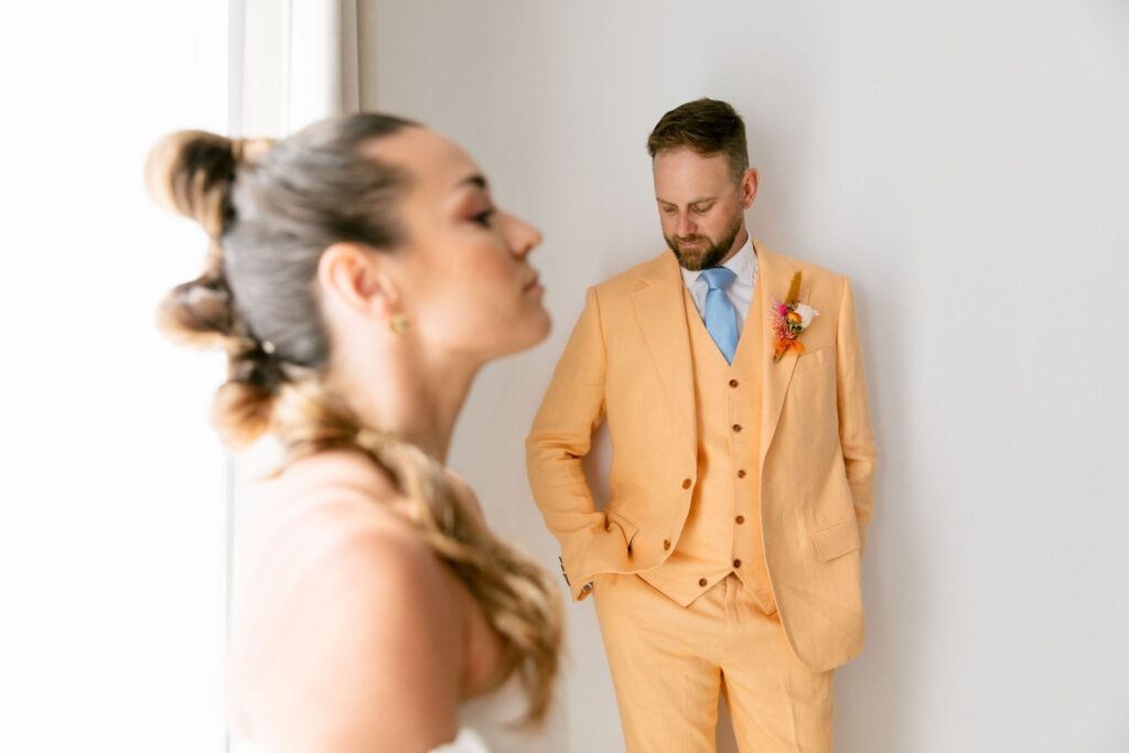 wedding portrait colorful mexico wedding colorful wedding style groom peach cotswold tailors suit with light blue tie and orange and pink boutenir. bride with mohawk high bubble pony tail strapless wedding gown. 