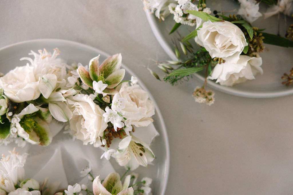 delicate white florals with simple greens boutenirs flat lay