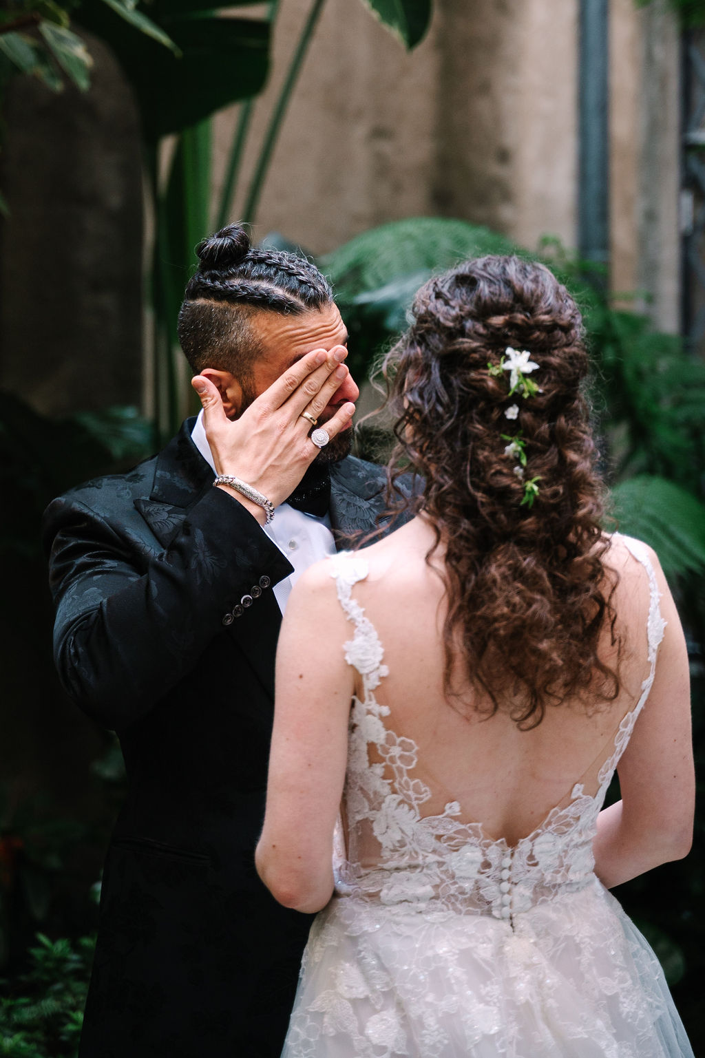groom portraits groom wedding style man braids classy satin black suit with floral details and sparkly sequenced bowtie berkeley city club courtyard wedding first look simple classic airy wedding dress with tule and lace detailing black and white portrait candid emotional crying in love