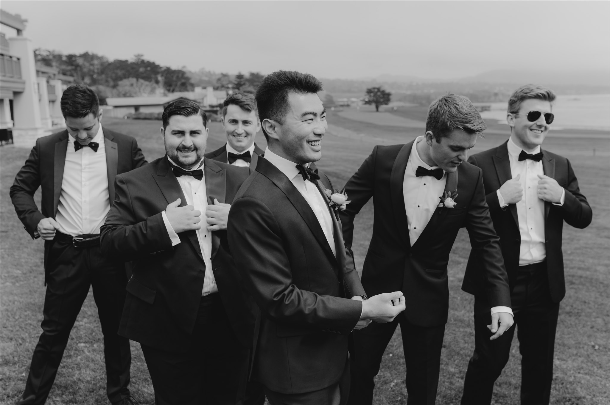 black and white groom portraits candid smiling beachside wedding carmel california black suits with black bowtie